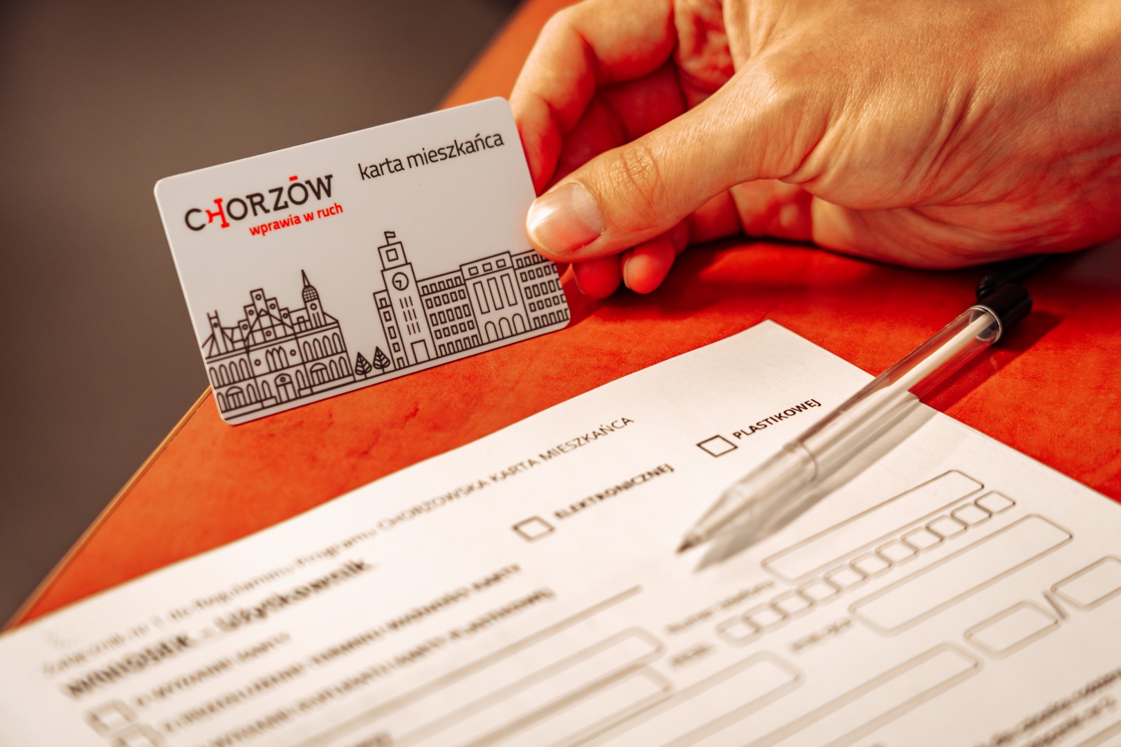 Dłoń trzymająca fizyczną Chorzowską Kartę Mieszkańca